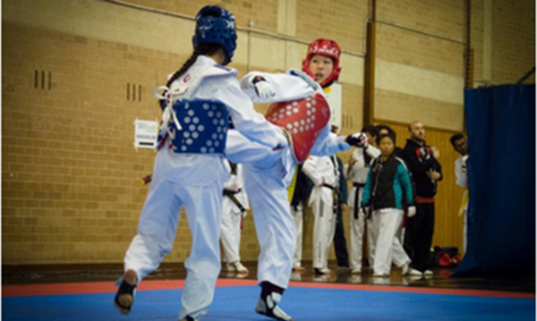 Two Tae Kwon Do club members are engaged in sparring while wearing protective gear