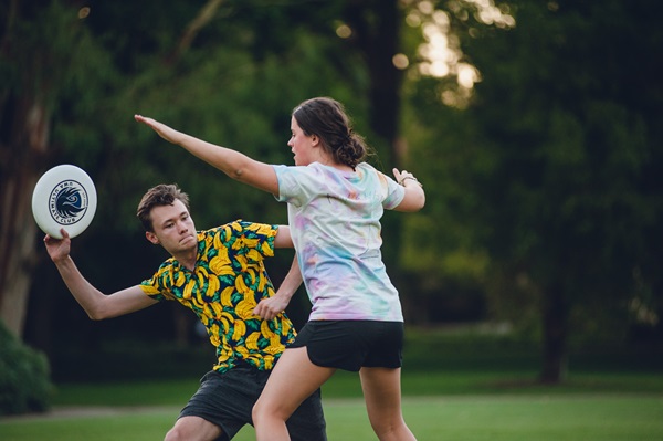 A student prepares to throw a frisbee, while another student attempts to block the throw
