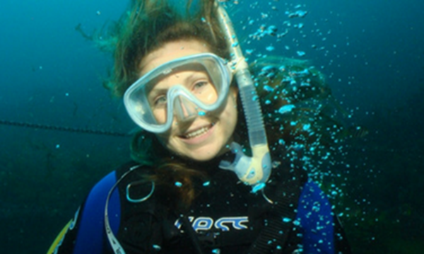 An Underwater Club member wearing a snorkel and wetsuit smiles while diving