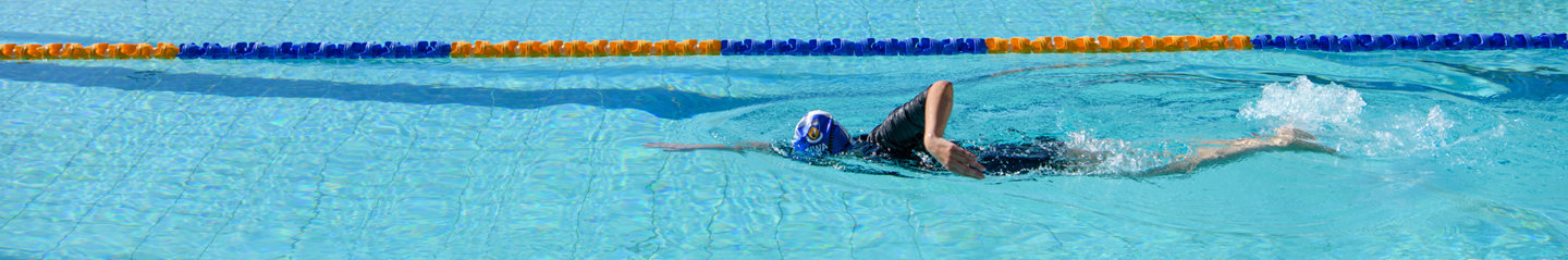 An adult swimmer swims freestyle in a clear blue pool
