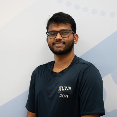 "Shrudeep, a UWA Sport employee, stands smiling in front of Waagyl mural"