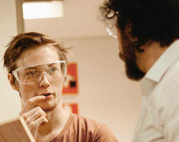 Student in safety glasses talking to instructor
