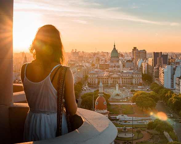 Student looking over a cityscape from a small balcony, in late afternoon golden sunlight