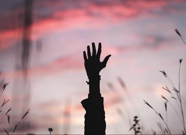 Image of hand in the air with sunset behind