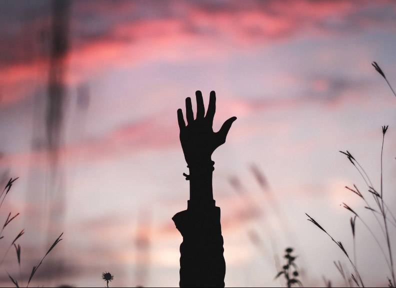Image of hand in the air with sunset behind