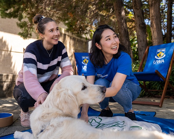 Two students playing with dog