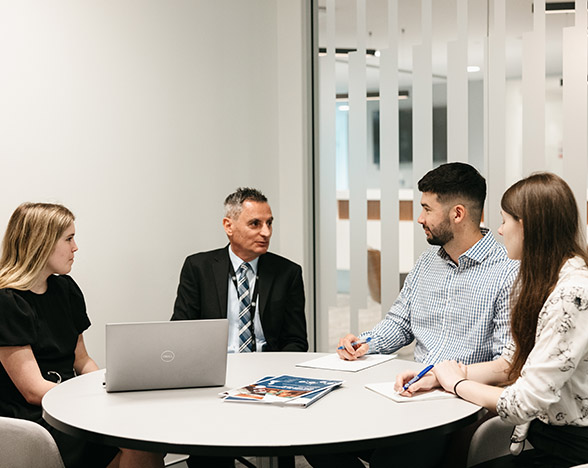 Three students sitting at desk with male mentor