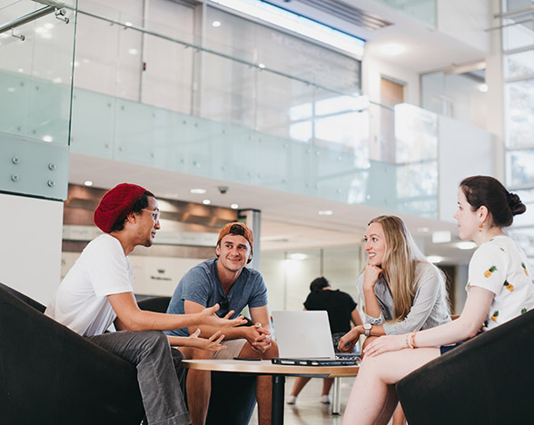 Students sitting around a table in large foyer