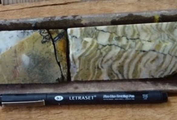 Pen laying next to a cross section of rock