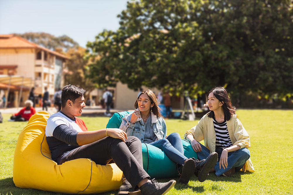 Three students sitting on beanbags on lawn at UWA