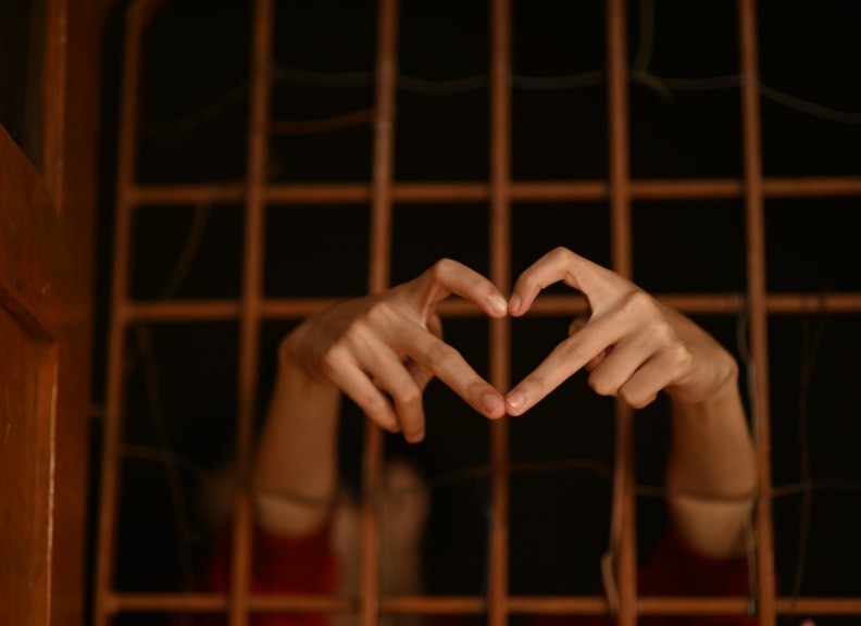 Hands forming heart outside of prison bars