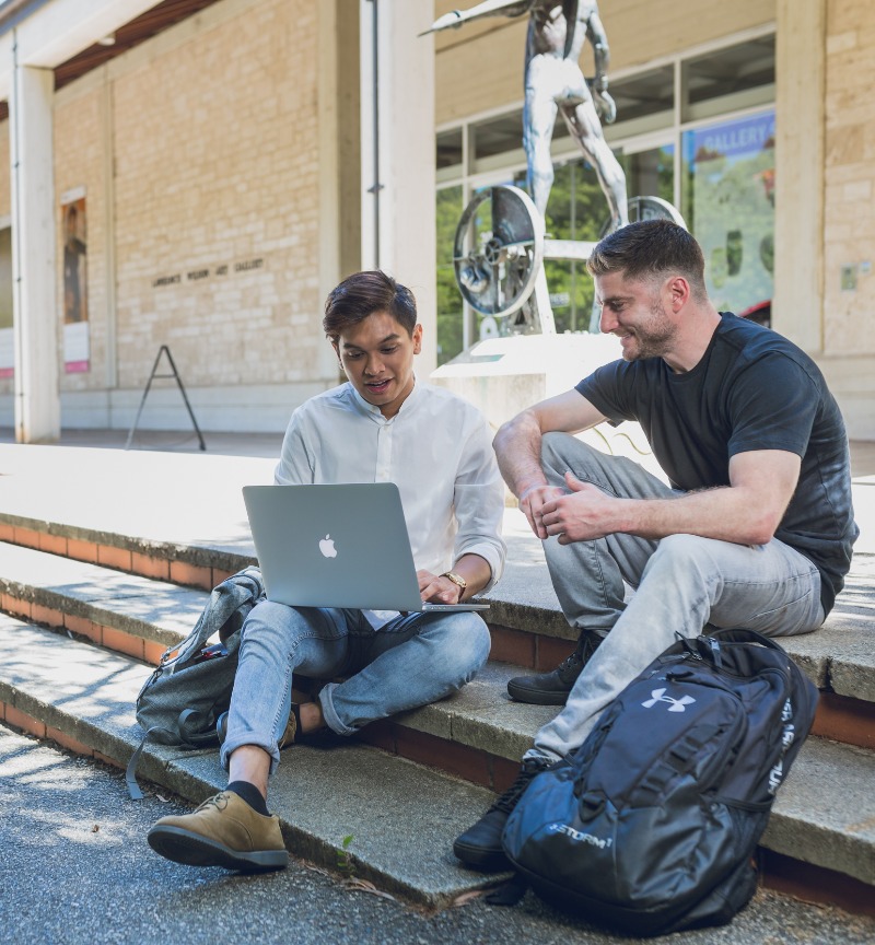 Two people sitting on the steps outside a museum 