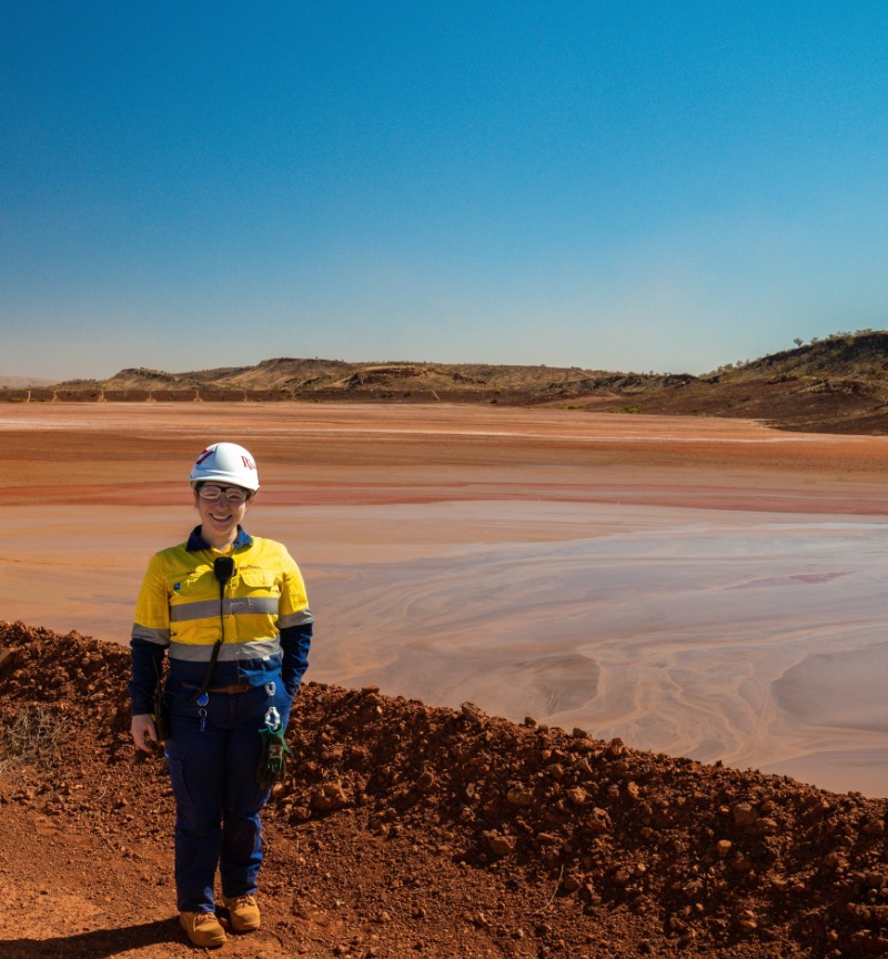 Mining engineer graduate standing in front of Tailings Dam
