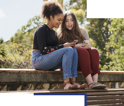 2 girls lookign at their phone while sitting on steps