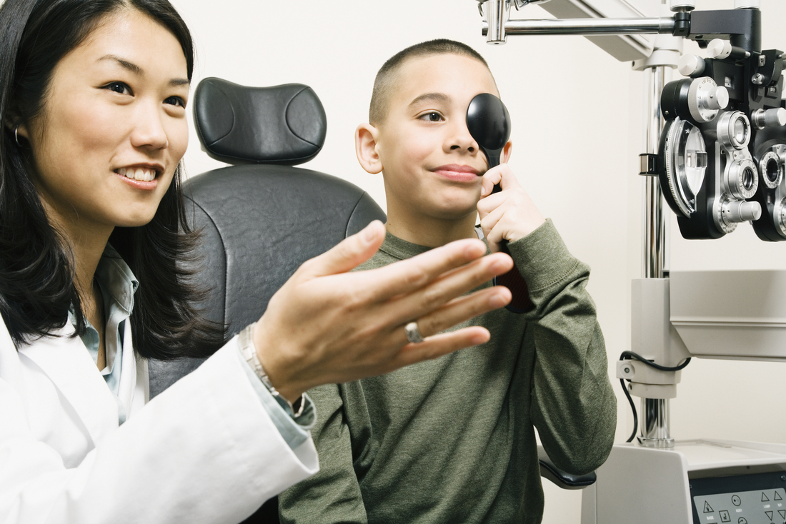Female optometrist conducting a vision test on a young boy