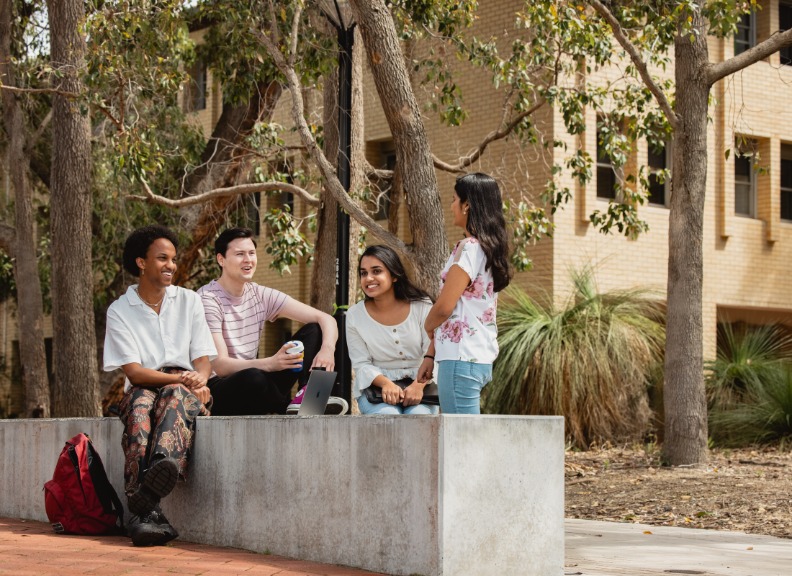 Four students sitting on campus talking